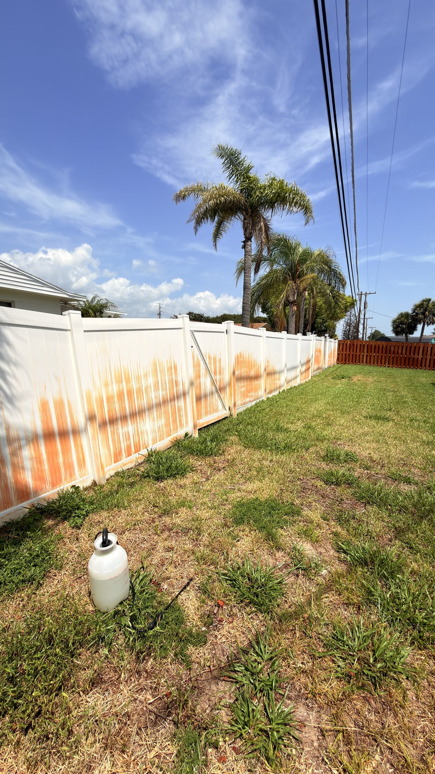 Vinyl fence before, streaked with rust